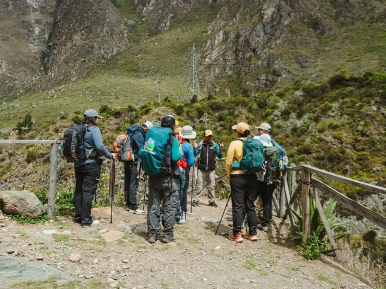 A local tour guide explaining the route to a group of hikers on a mountain path, used to illustrate the etiquette for tipping in Peru after an Inca Trail trek.