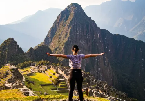Traveler with arms outstretched above Machu Picchu