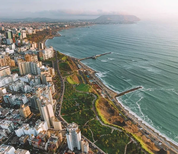 Costa Verde Beach in Lima with surfers riding the waves of the Pacific Ocean and the urban landscape of the Peruvian capital above the cliffs.