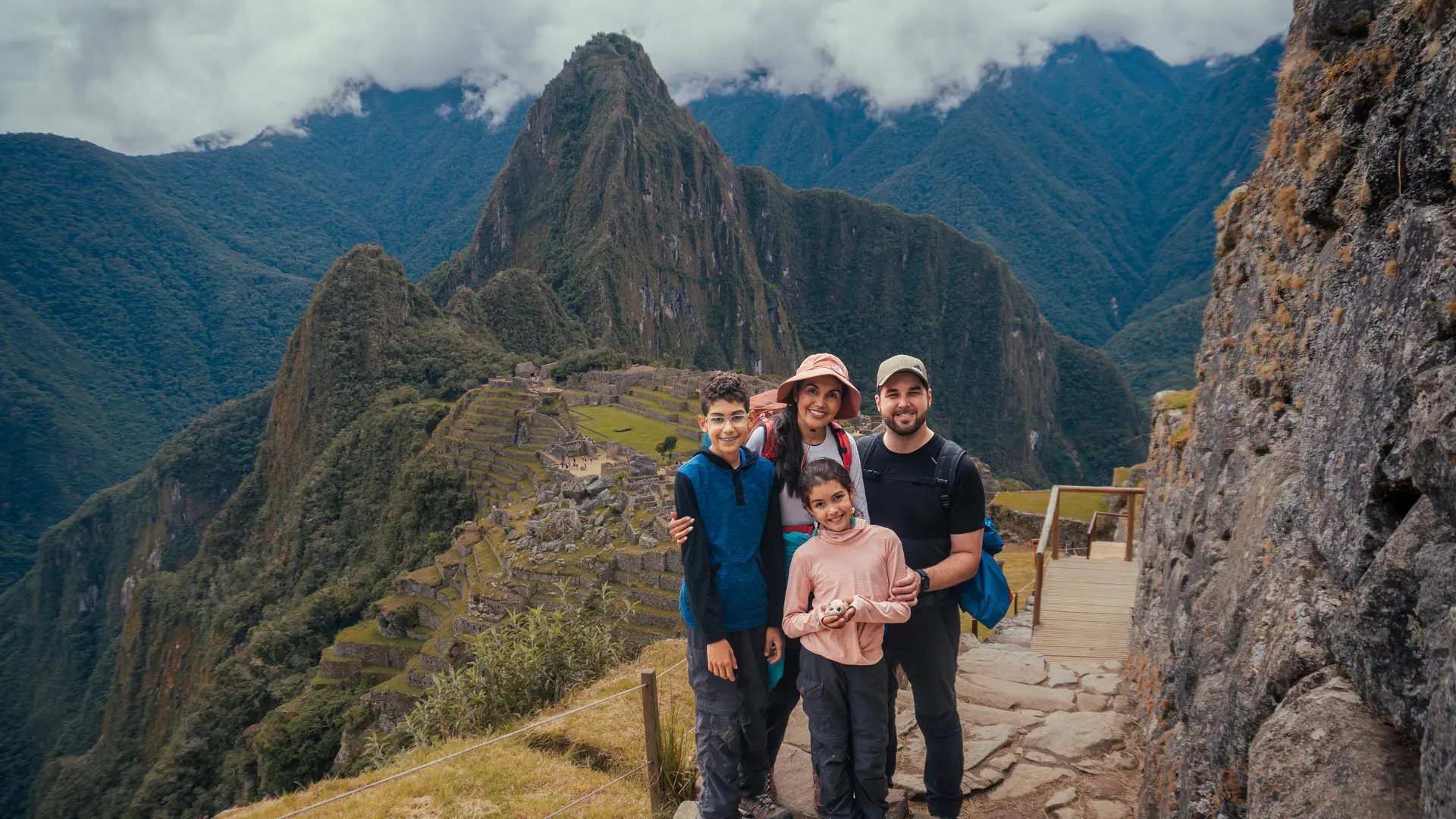 family enjoying one of the best machu picchu tours at the classic viewpoint with huayna picchu mountain in the background