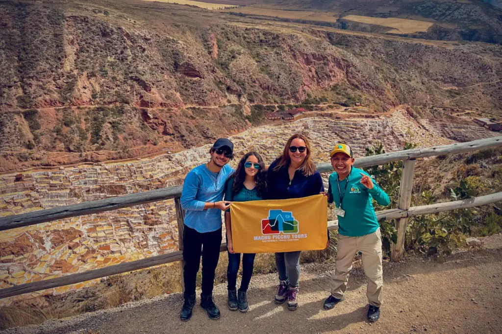 Family holding Machu Picchu Tours banner at Maras salineras on half day tour from Cusco